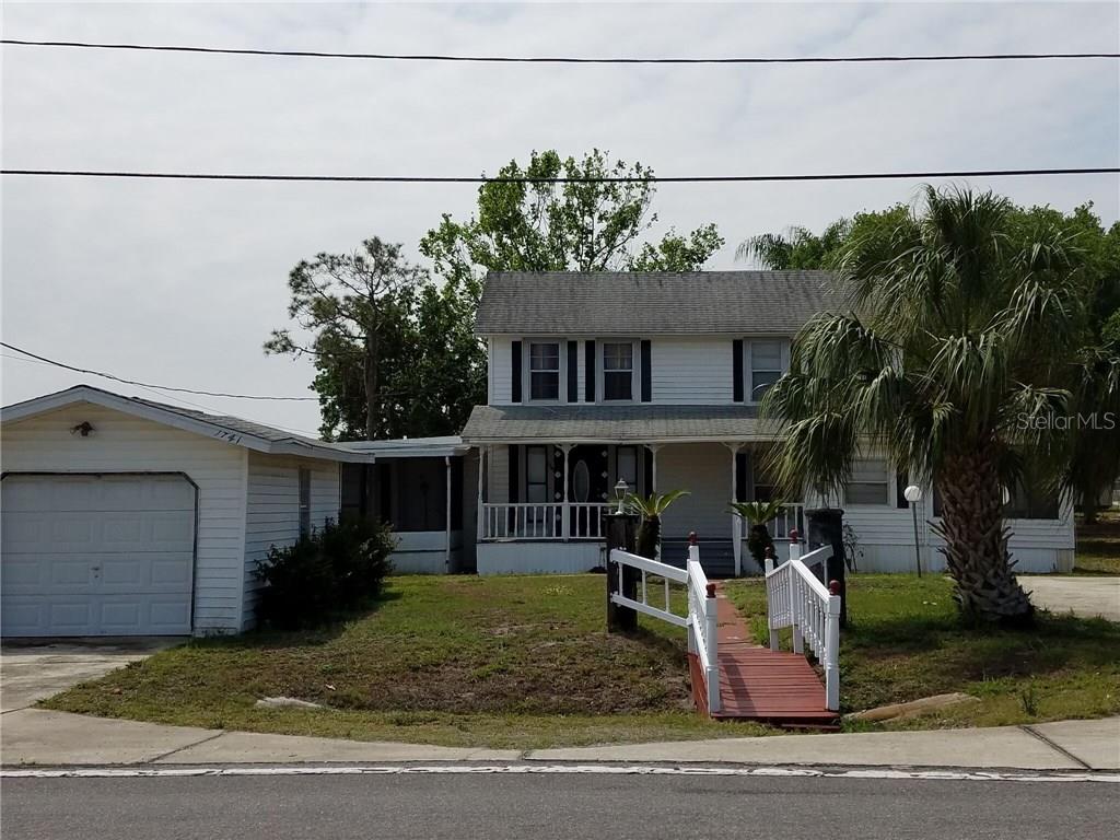 a view of a white house with a small yard plants and palm trees