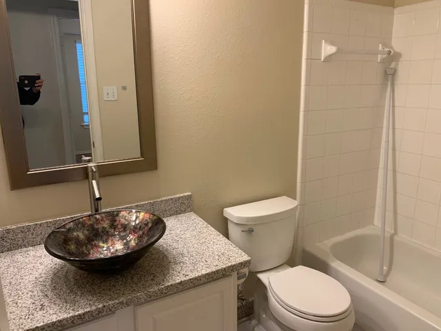 a bathroom with a sink a toilet a mirror and shower