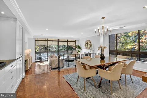 a view of a dining room with furniture a chandelier and large windows