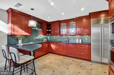 a kitchen with stainless steel appliances granite countertop a refrigerator a sink and wooden cabinets