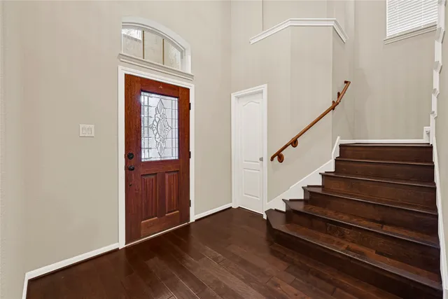 an empty room with wooden floor chandelier fan and windows