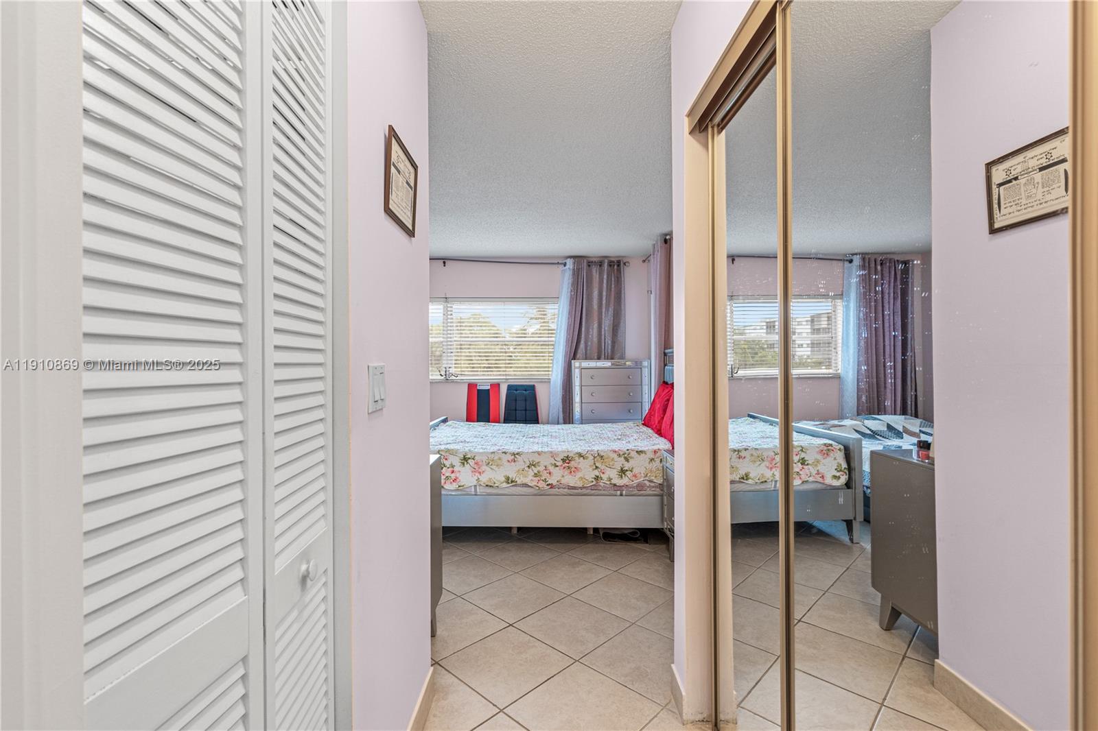 1425 Atlantic Shores Boulevard, Unit 409 Hallandale Beach, FL 33009 - Photo 17 of 30 a bedroom with a bed and a mirror