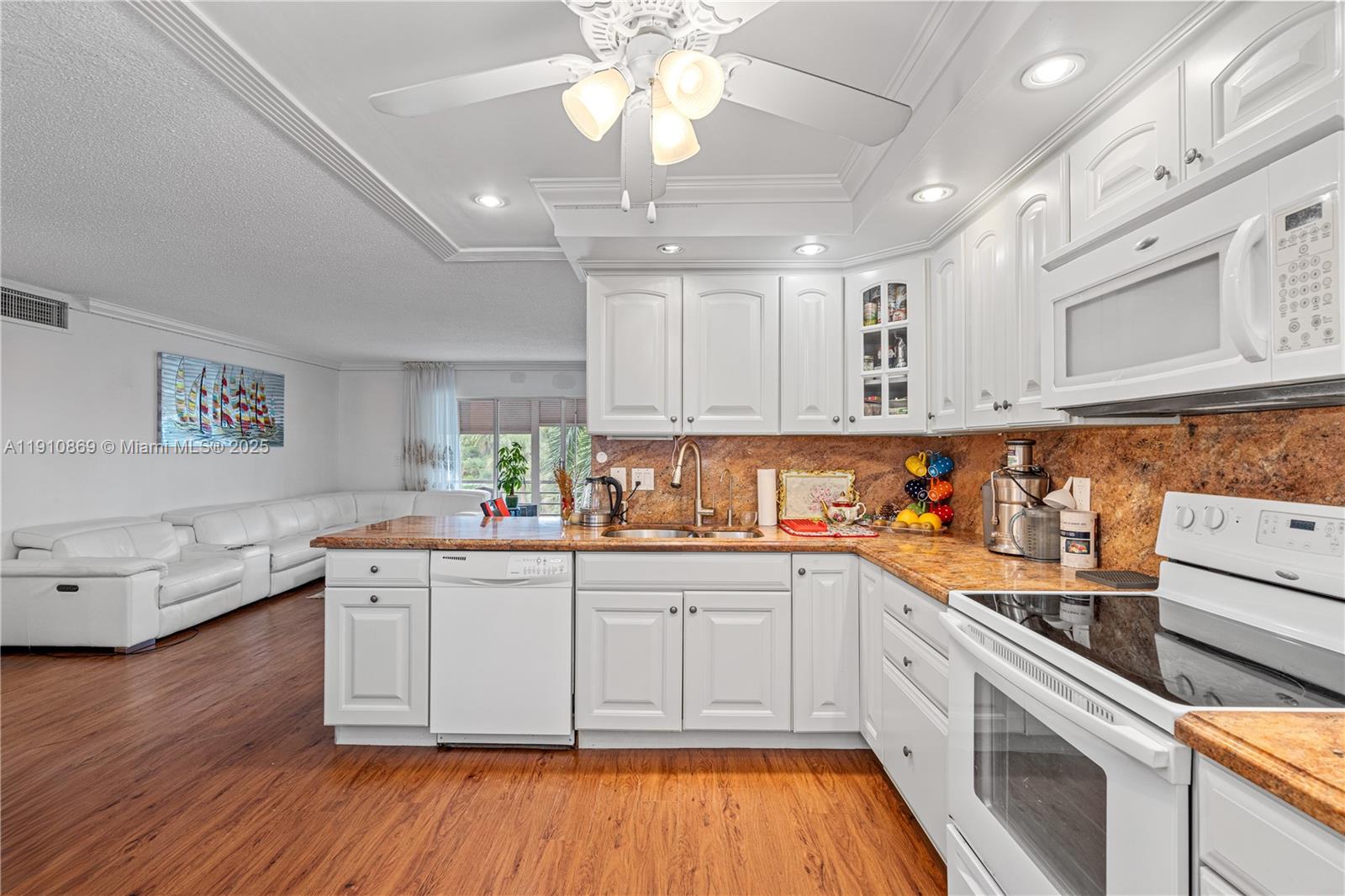 1425 Atlantic Shores Boulevard, Unit 409 Hallandale Beach, FL 33009 - Photo 3 of 30 a white kitchen with stainless steel appliances granite countertop a sink dishwasher a stove and white cabinets with wooden floor