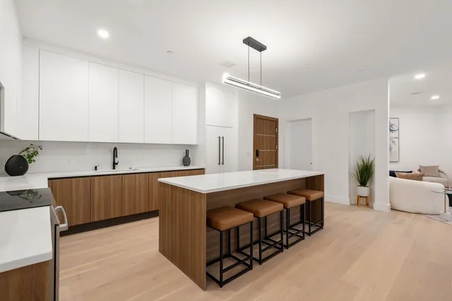 a kitchen with stainless steel appliances a sink stove and wooden floor