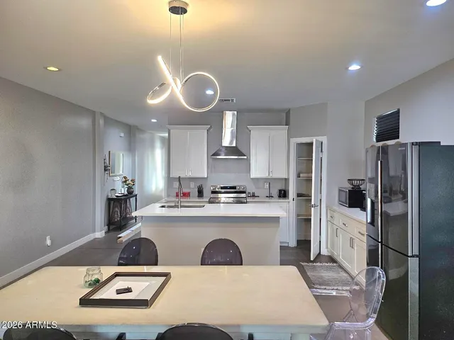 a kitchen with stainless steel appliances a table chairs and a refrigerator