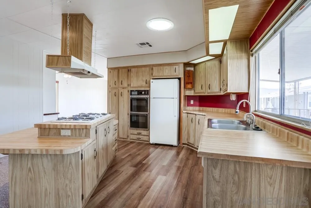 650 South Rancho Santa Fe Road, Unit 44 San Marcos, CA 92078 - Photo 12 of 25 a kitchen with a stove a refrigerator and a stove with wooden floor