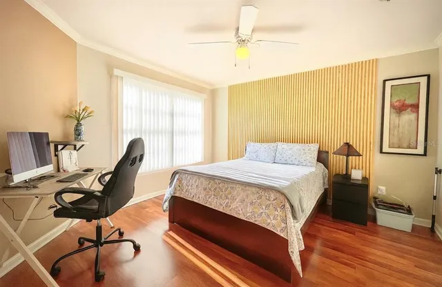 a bedroom with a bed a desk and chair with wooden floor