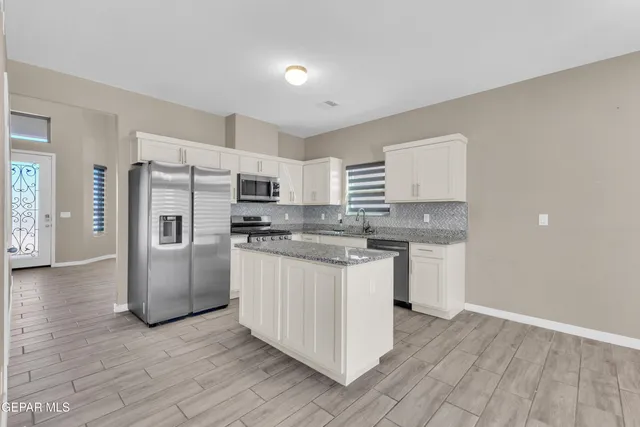 a kitchen with stainless steel appliances granite countertop a refrigerator and a stove top oven