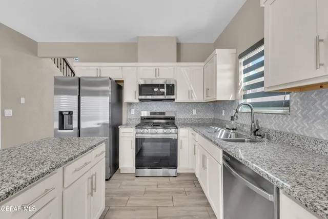 a kitchen with stainless steel appliances granite countertop a sink stove and refrigerator
