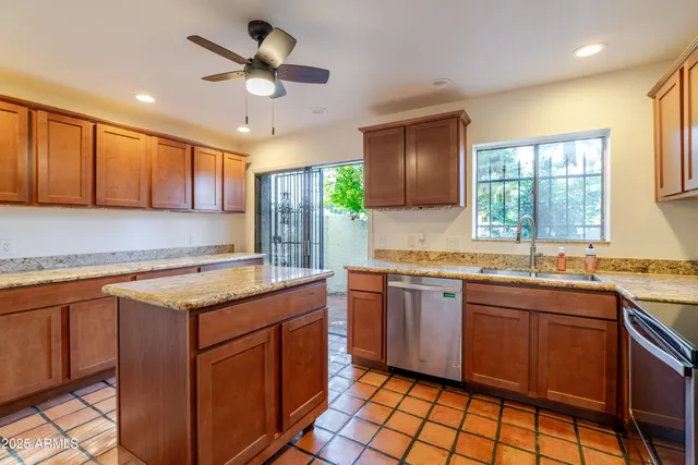 a kitchen with stainless steel appliances granite countertop a refrigerator a sink a stove a washer and a refrigerator