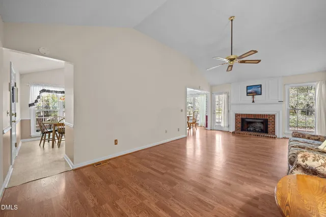 a view of a livingroom with furniture wooden floor a ceiling fan and windows