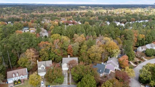 an aerial view of a house with a yard and trees all around