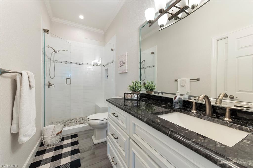10910 Ruden Road North Fort Myers, FL 33917 - Photo 20 of 48 a bathroom with a granite countertop sink a toilet a mirror and shower