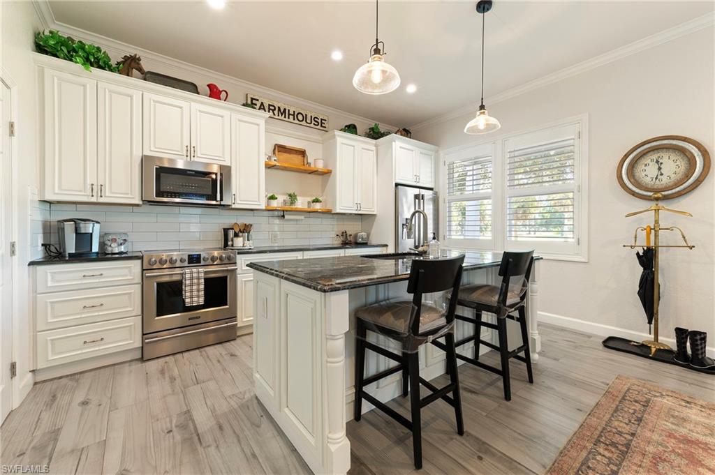 10910 Ruden Road North Fort Myers, FL 33917 - Photo 24 of 48 a kitchen with stainless steel appliances kitchen island granite countertop a stove top oven a sink a dining table and chairs with wooden floor