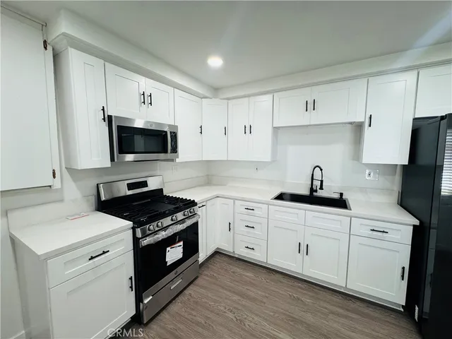a kitchen with granite countertop white cabinets sink and stainless steel appliances