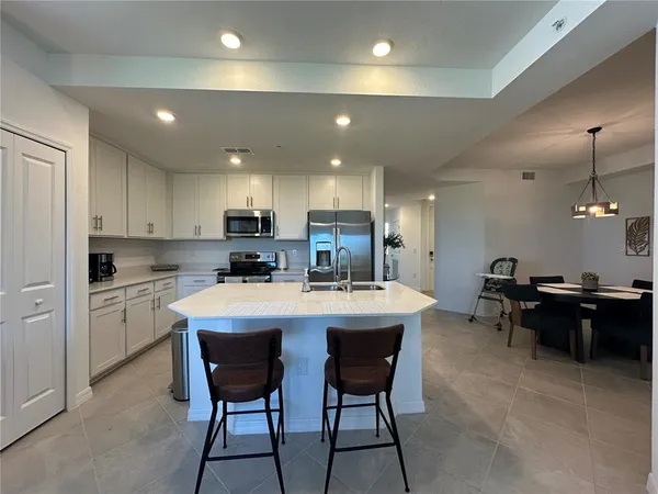a kitchen with a sink a stove and chairs with wooden floor