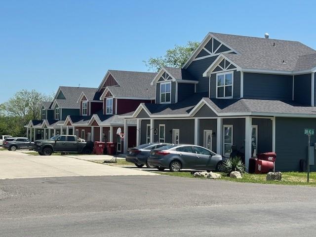 a front view of a house with a yard and large trees