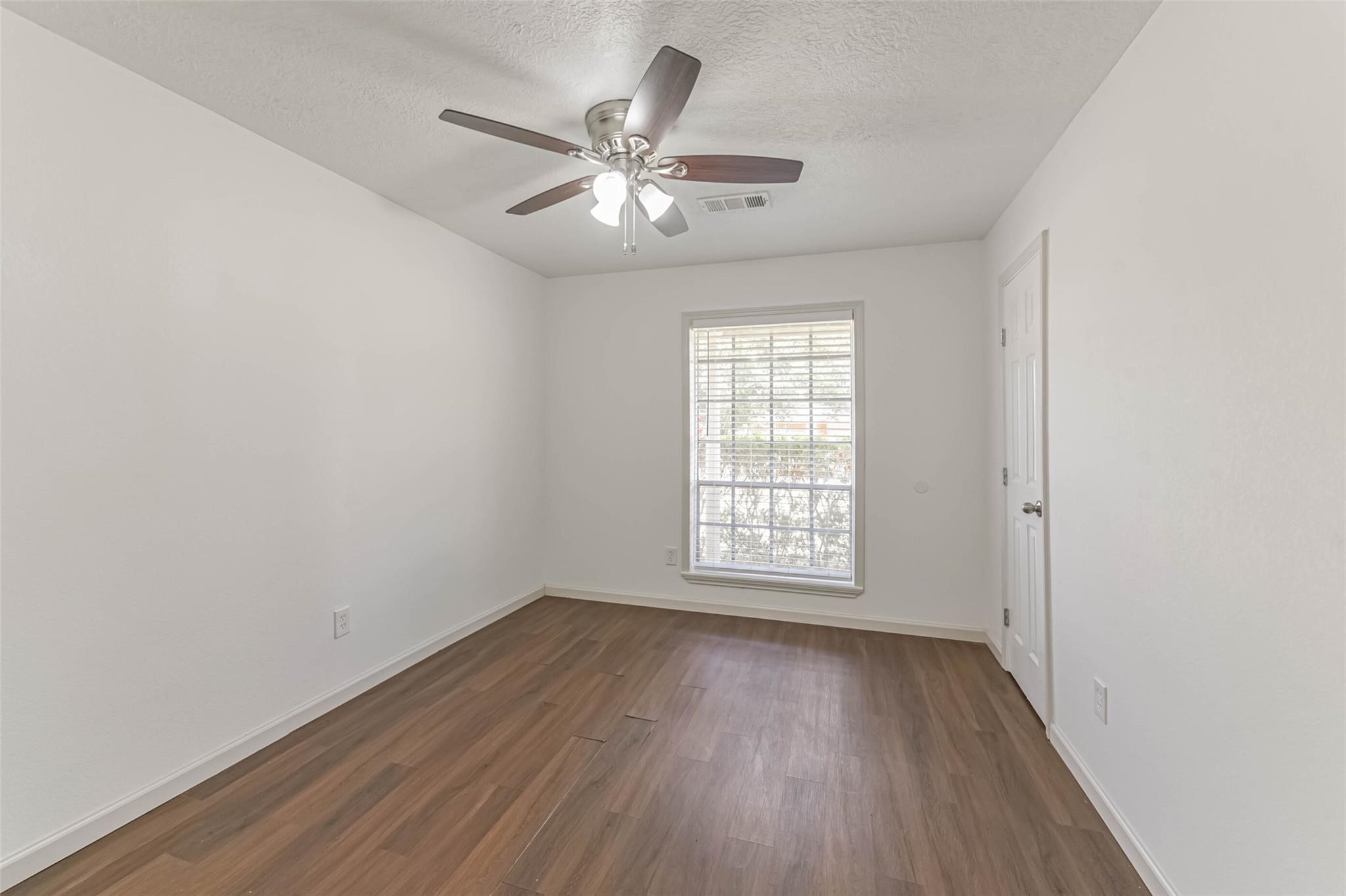 12002 Palmcroft Street Houston, TX 77034 - Photo 13 of 16 an empty room with wooden floor chandelier fan and windows