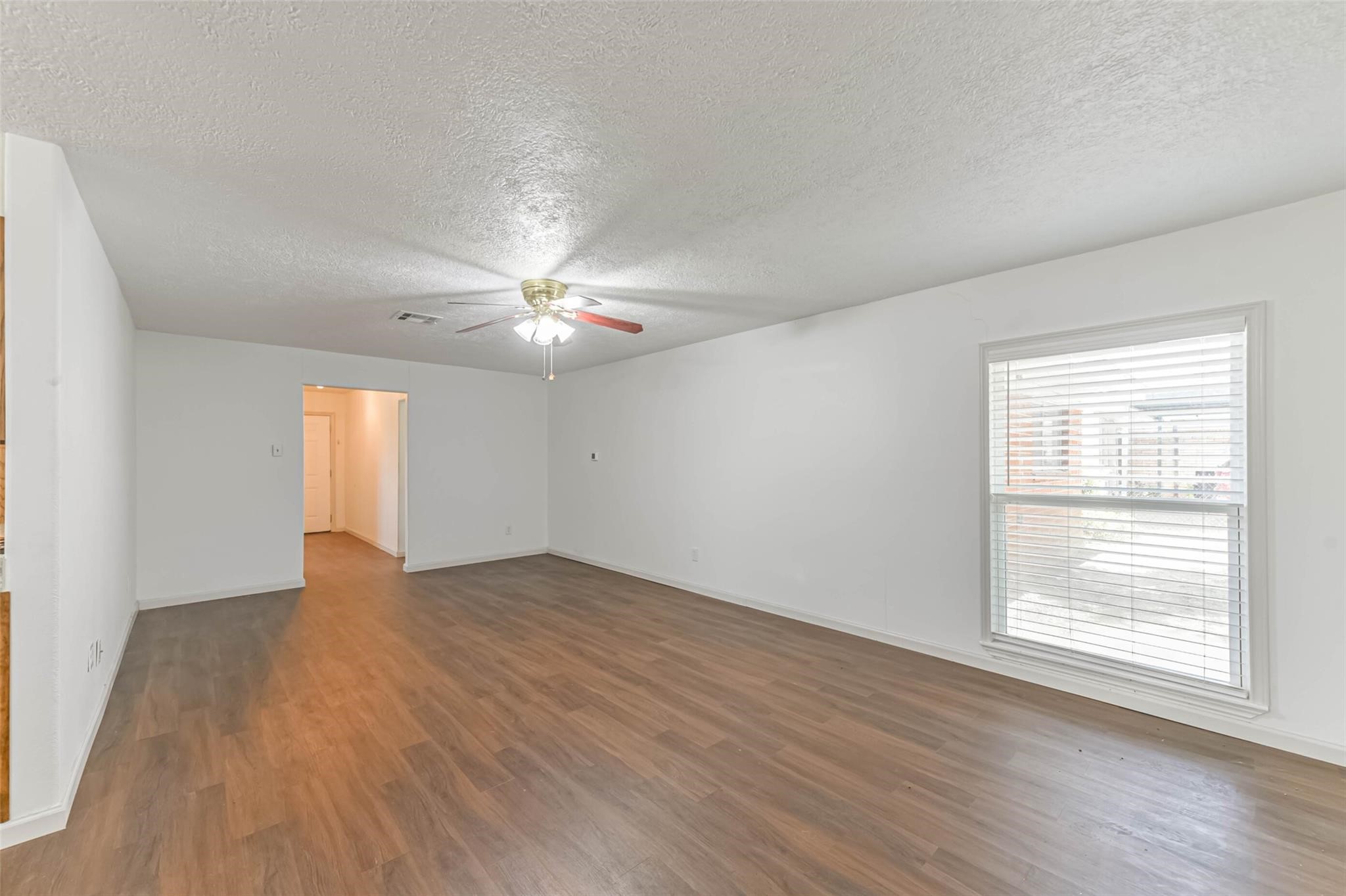 12002 Palmcroft Street Houston, TX 77034 - Photo 6 of 16 an empty room with wooden floor chandelier fan and windows