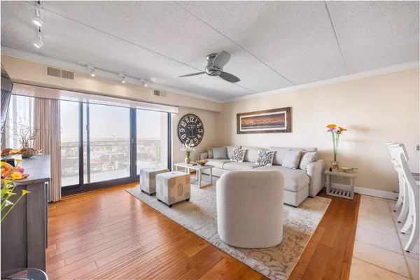 a living room with furniture large windows and wooden floor
