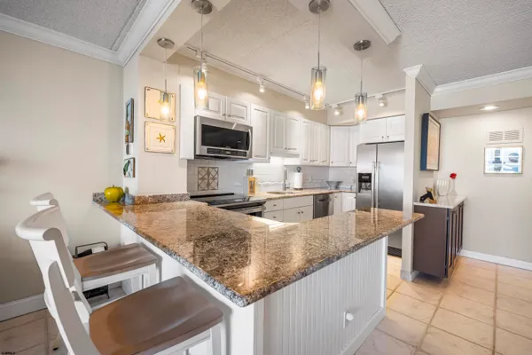 a kitchen with kitchen island granite countertop a sink refrigerator and microwave
