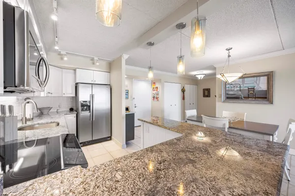a kitchen with stainless steel appliances kitchen island granite countertop a refrigerator and a sink