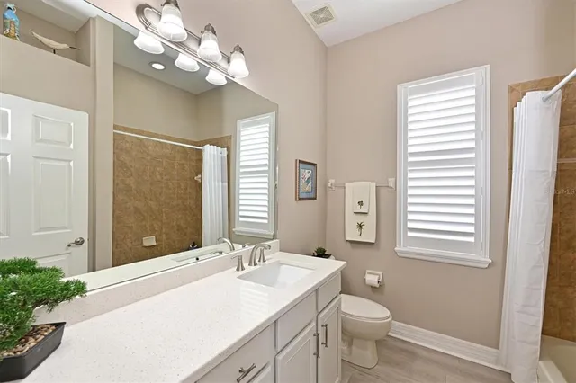 a bathroom with a toilet a sink a large mirror and vanity