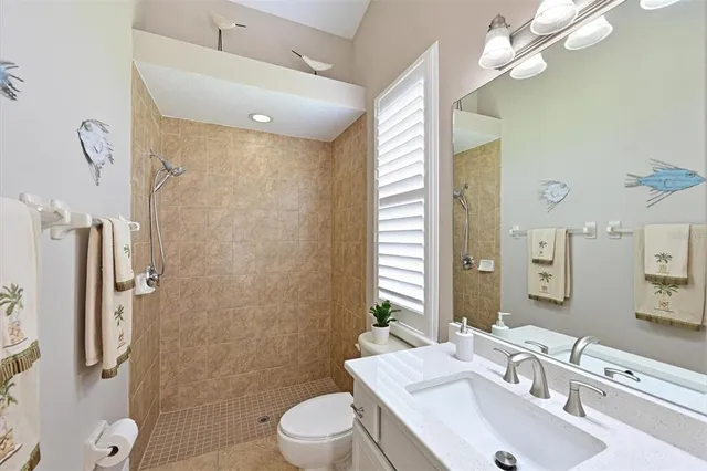 a bathroom with a sink a toilet a mirror and shower