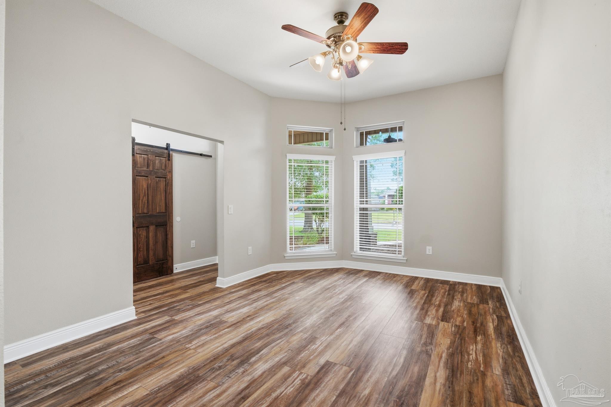 5661 Cane Syrup Circle Pace, FL 32571 - Photo 3 of 20 an empty room with wooden floor chandelier fan and windows