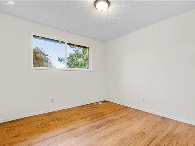 an empty room with wooden floor and window