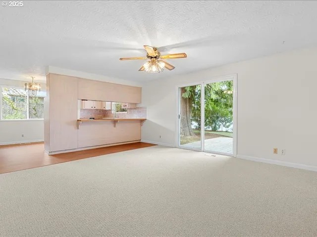 an empty room with windows and ceiling fan