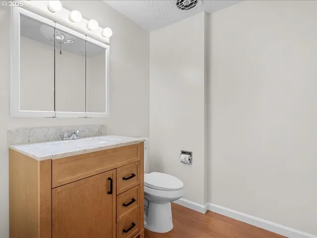 a bathroom with a granite countertop toilet a sink and a mirror