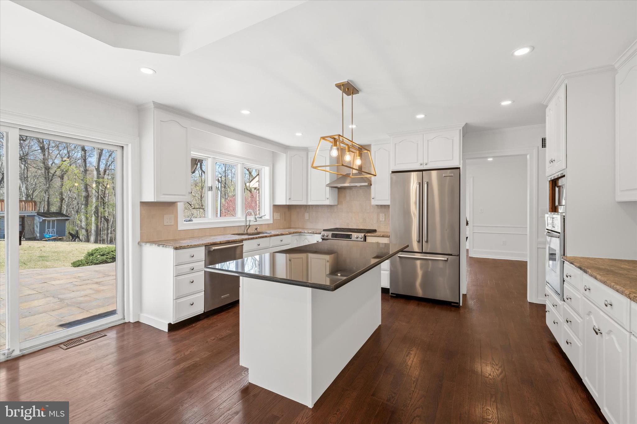 411 Hidden Valley Road Media, PA 19063 - Photo 30 of 90 a kitchen with stainless steel appliances kitchen island granite countertop a refrigerator a sink dishwasher a stove and a dining table with wooden floor