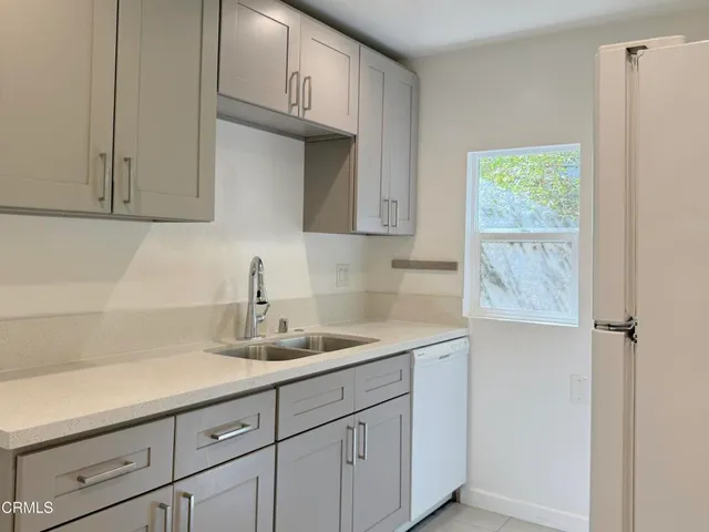 a kitchen with white cabinets and a window