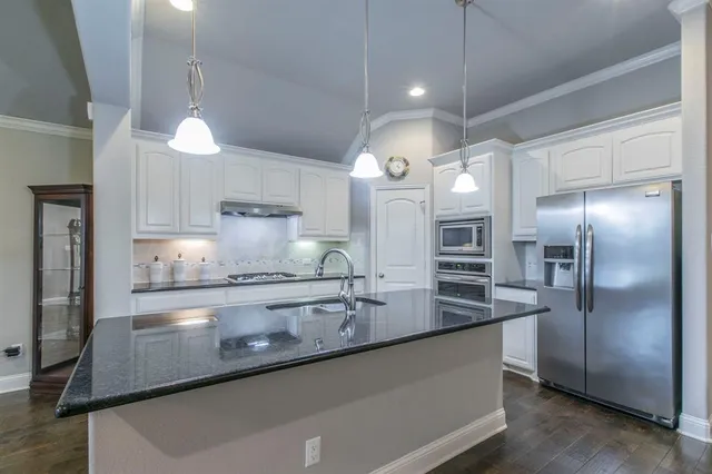 a kitchen with stainless steel appliances granite countertop a refrigerator a sink and a stove