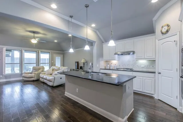 a kitchen with counter top space sink stove and wooden floor