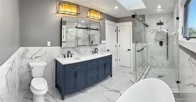 a spacious bathroom with a bathtub shower sink mirror and toilet