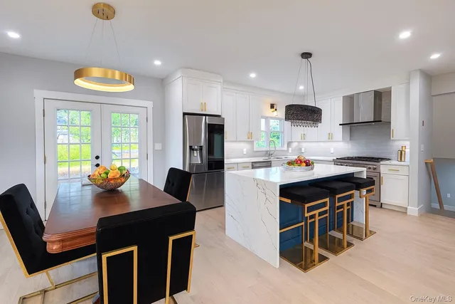 a kitchen with stainless steel appliances a sink a stove a refrigerator a dining table and chairs with wooden floor