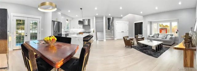 a living room with stainless steel appliances furniture a rug and a kitchen view