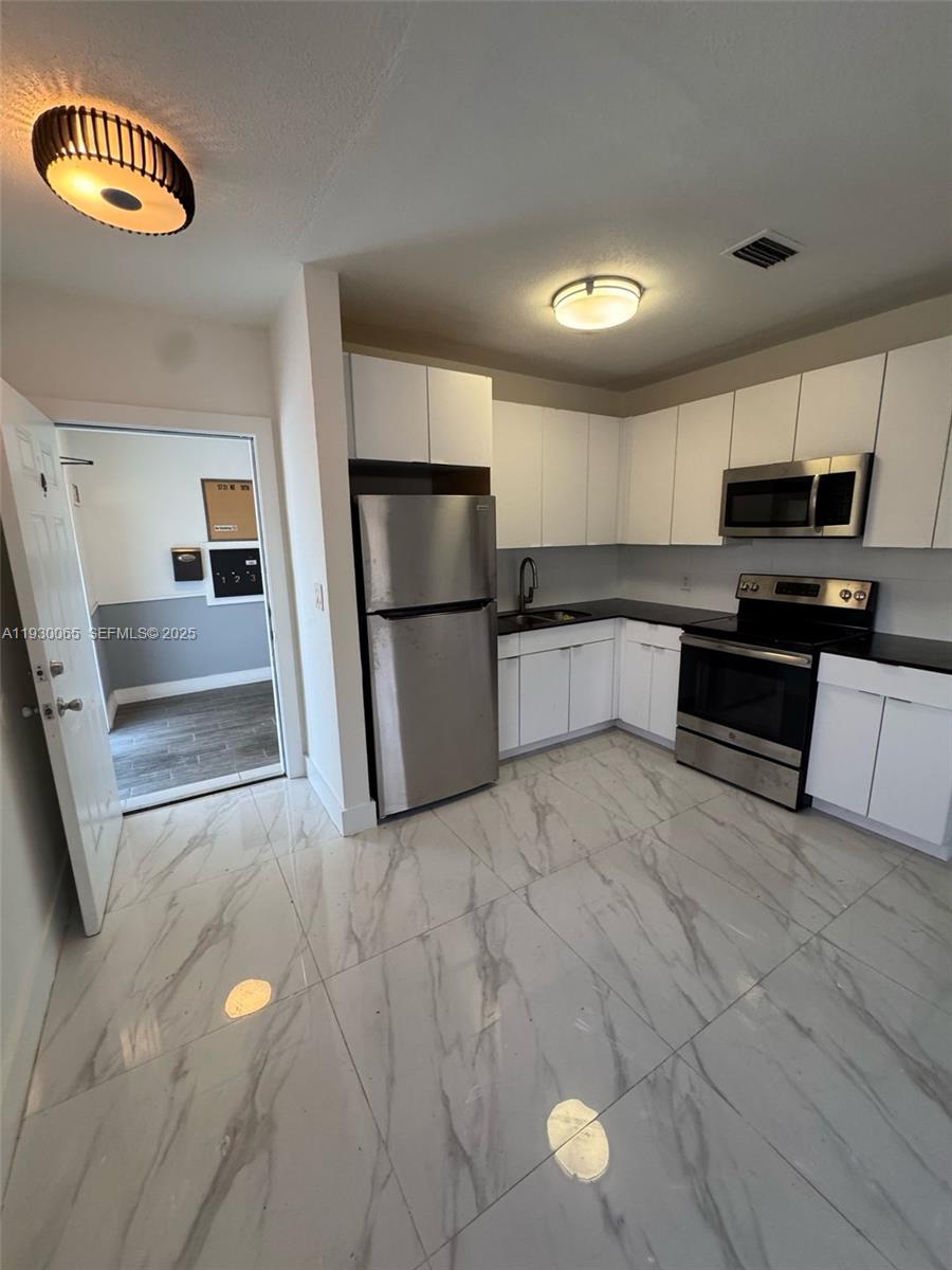 5731 Northeast 18th Avenue, Unit 4 Fort Lauderdale, FL 33334 - Photo 2 of 13 a kitchen with stainless steel appliances granite countertop a refrigerator a stove a sink and a microwave