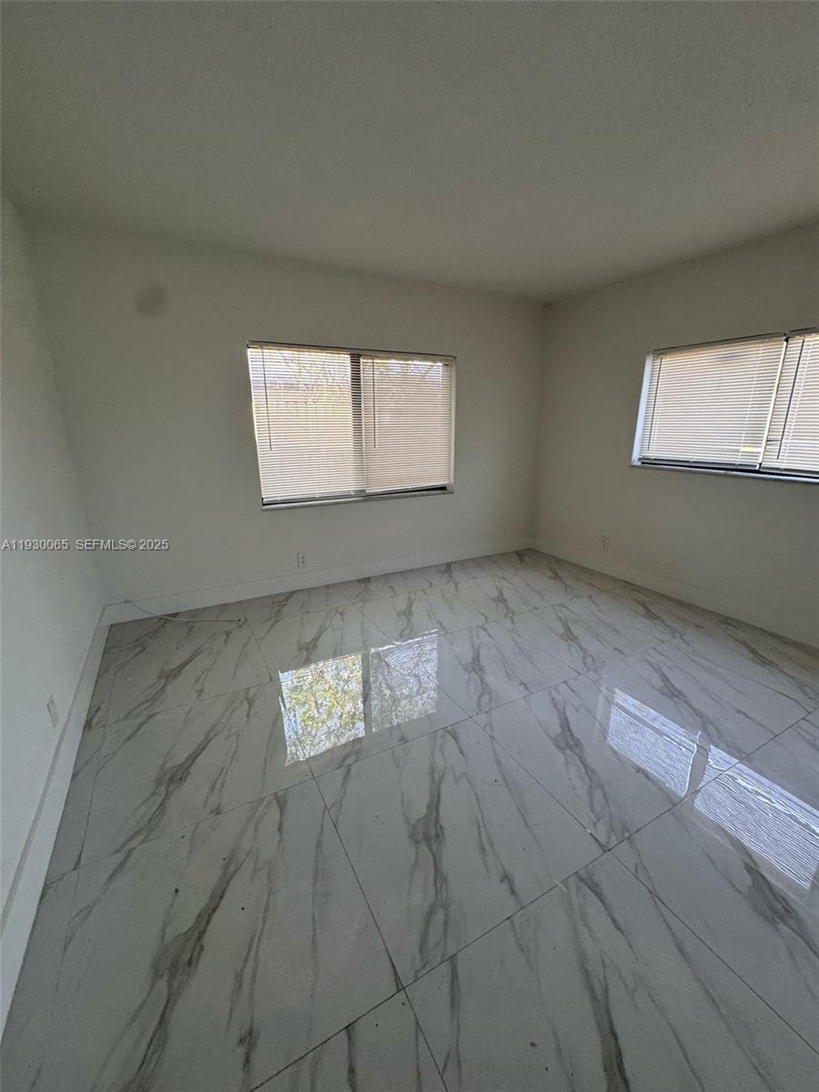 5731 Northeast 18th Avenue, Unit 4 Fort Lauderdale, FL 33334 - Photo 4 of 13 an empty room with wooden floor and windows