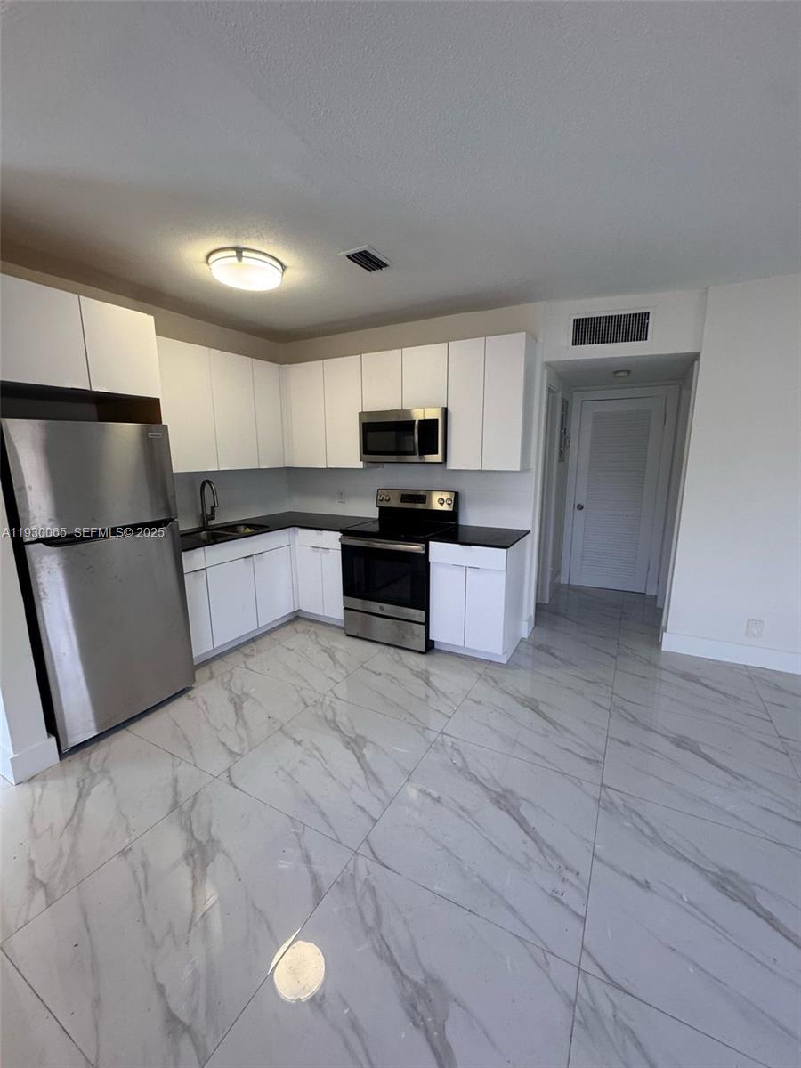 5731 Northeast 18th Avenue, Unit 4 Fort Lauderdale, FL 33334 - Photo 5 of 13 a kitchen with stainless steel appliances granite countertop a refrigerator and a stove top oven