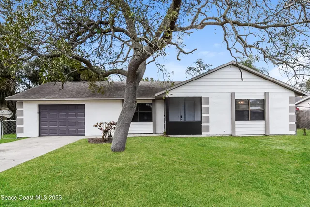a front view of a house with a yard and large tree