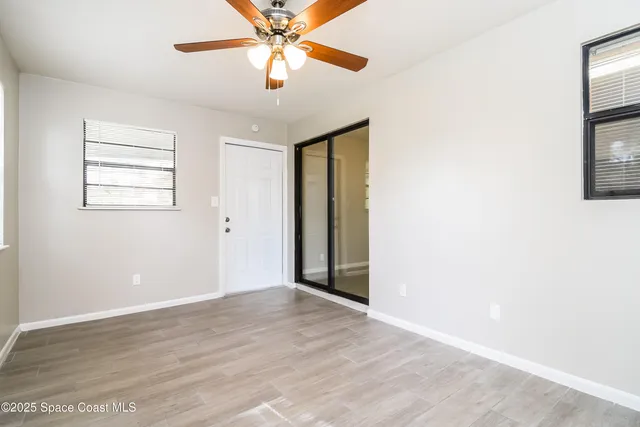 an empty room with windows and fan
