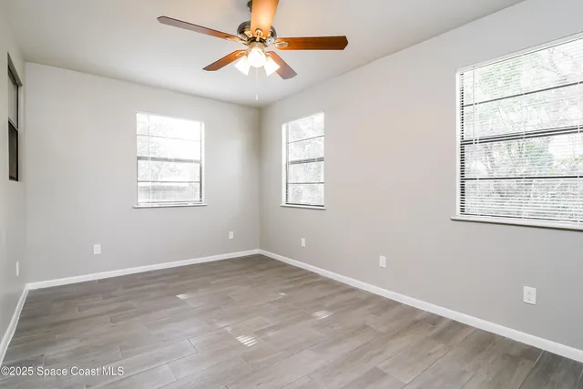 an empty room with windows and fan