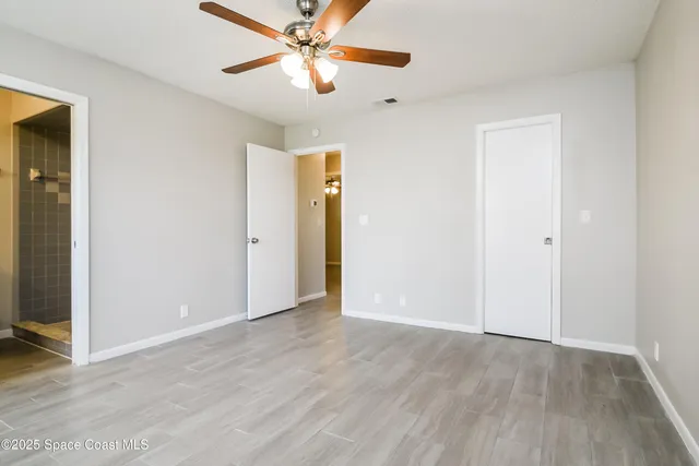 an empty room with closet and a chandelier fan