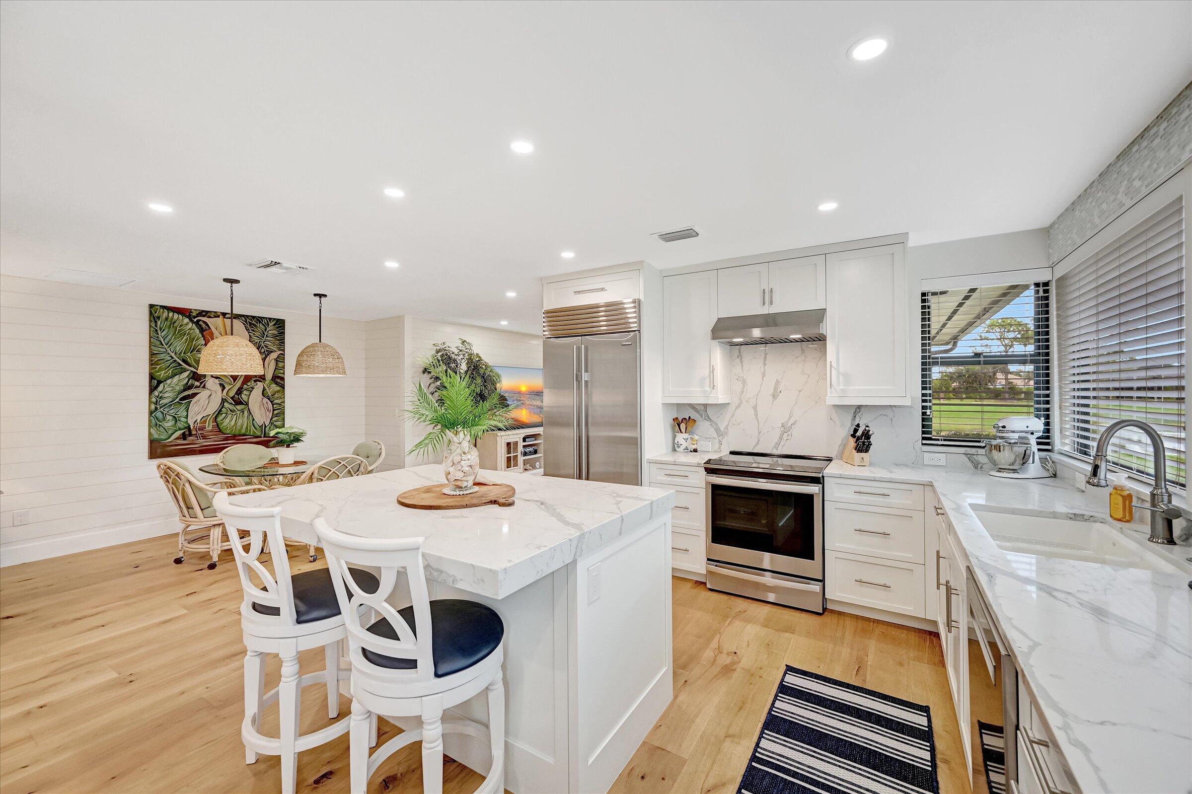535 Augusta Boulevard, Unit 4 Naples, FL 34113 - Photo 21 of 44 a kitchen with stainless steel appliances kitchen island granite countertop a stove a sink a dining table and chairs