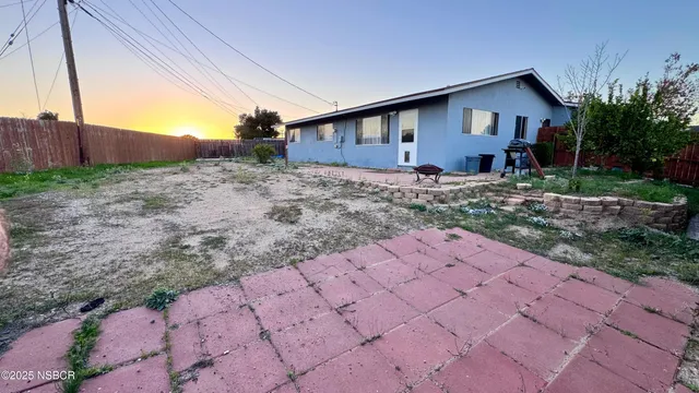 a view of house with backyard and bushes