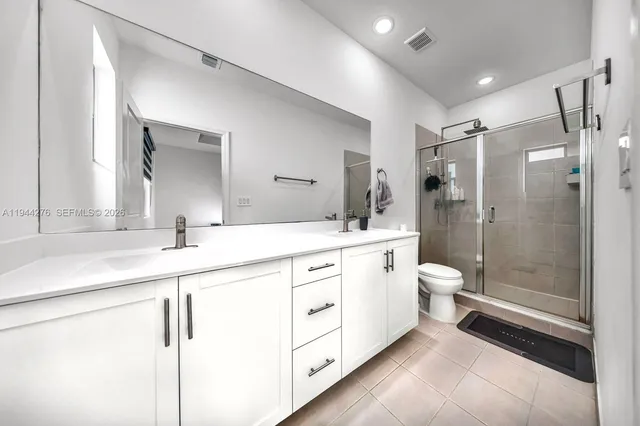 a spacious bathroom with a double vanity sink toilet mirror and shower