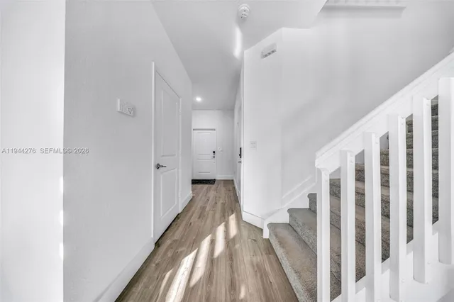 a view of a hallway with wooden floor and entryway